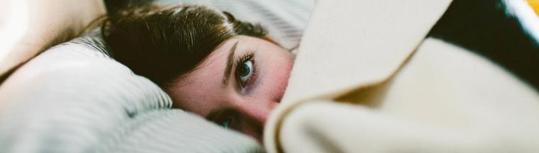 Foto van een vrouw die onder de dekens ligt